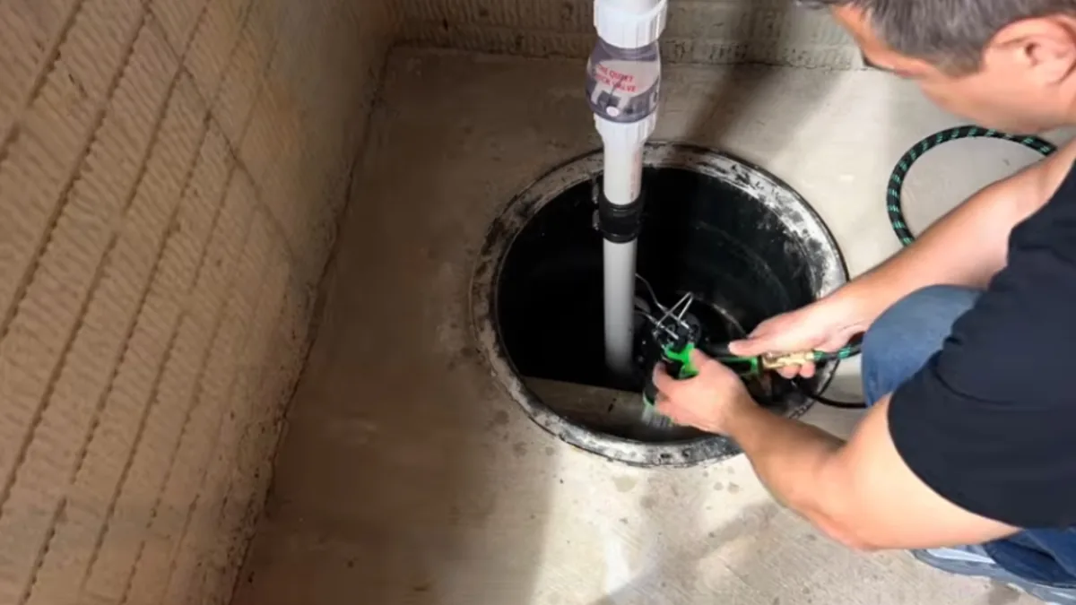 Technician servicing a sump pump in a basement pit
